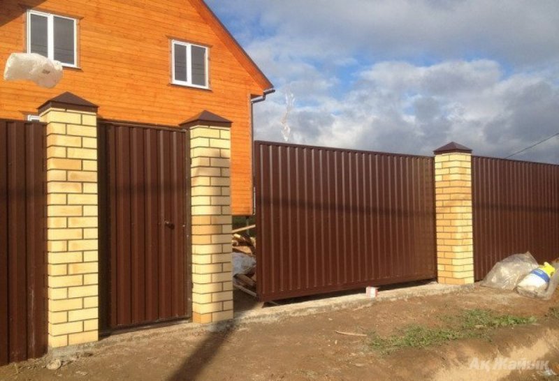 Забор из профлиста с кирпичными столбами и откатными воротами