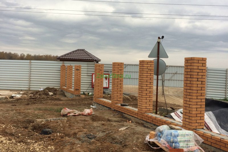 Забор из кирпичных столбов и кирпича