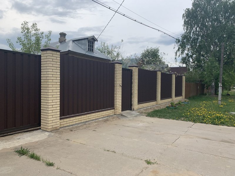 Забор из металлического штакетника с кирпичными столбами