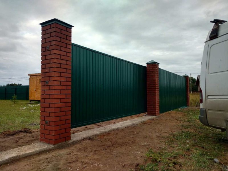 Забор из профлиста с кирпичными столбами и откатными воротами