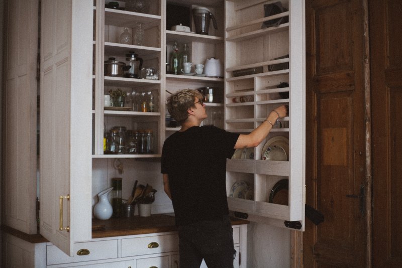 Girl tries to reach Cupboard