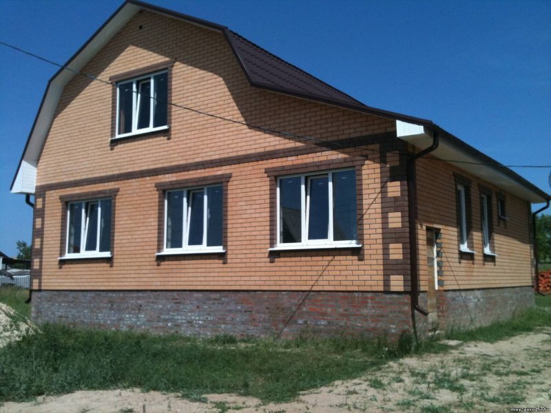 Одноэтажный дом из желтого кирпича с коричневыми окнами