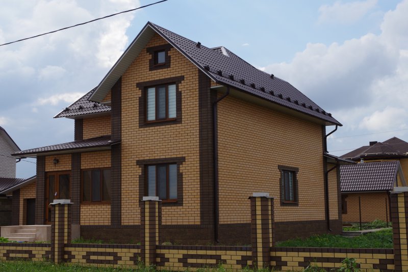 Дом из желтого кирпича с коричневой крышей