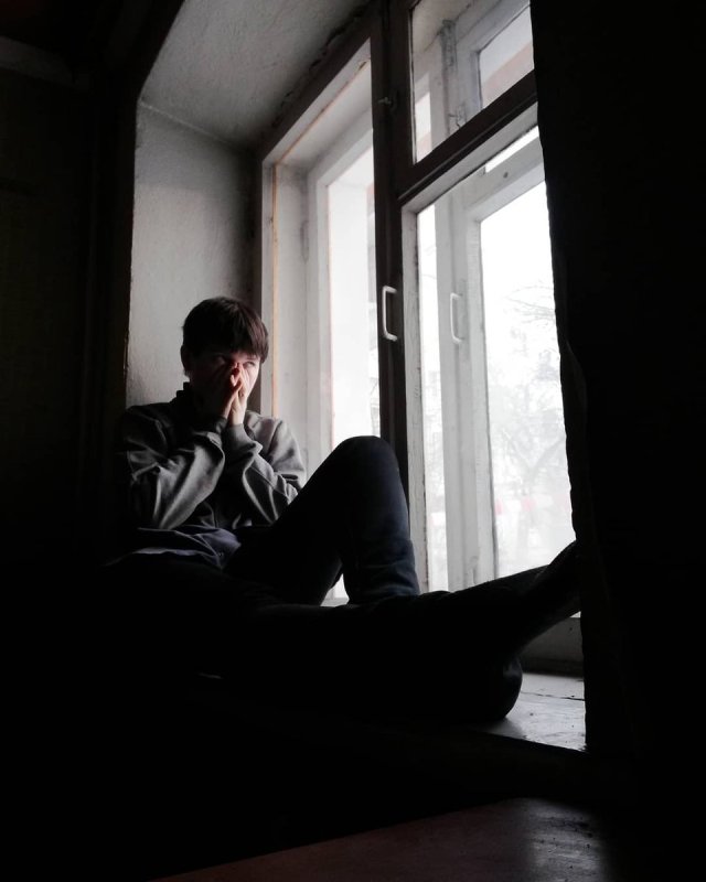 Человек сидит на подоконнике